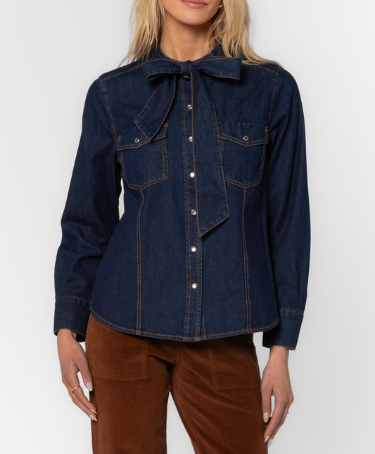 Denim Top with Pearl snap buttons going all the way down. This top has functional Pockets and a Bow at the neckline for a trendy chic appearnace.