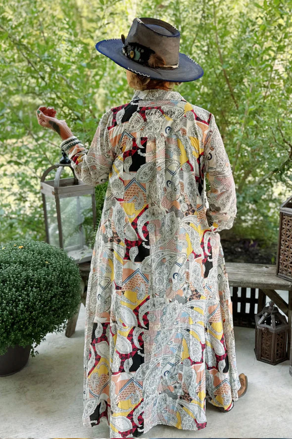 Woman wearing the Paisley Skies Duster Dress by Jaded Gypsy featuring colorful paisley print, hand-painted mandala buttons, and flowing lightweight cotton fabric.