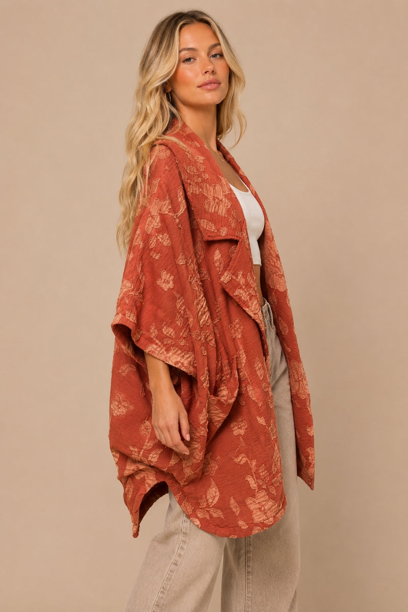 Side view of oversized brick floral applique kimono by J.NNA with wide three-quarter sleeves and flowing drape