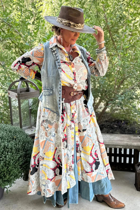 Woman wearing the Paisley Skies Duster Dress by Jaded Gypsy featuring colorful paisley print, hand-painted mandala buttons, and flowing lightweight cotton fabric.
