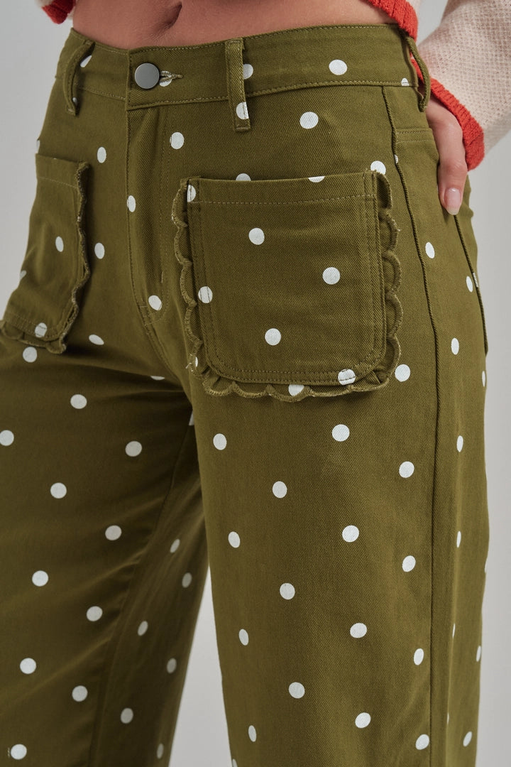 Close-up of olive polka dot twill pants featuring scalloped patch pockets and button waist.