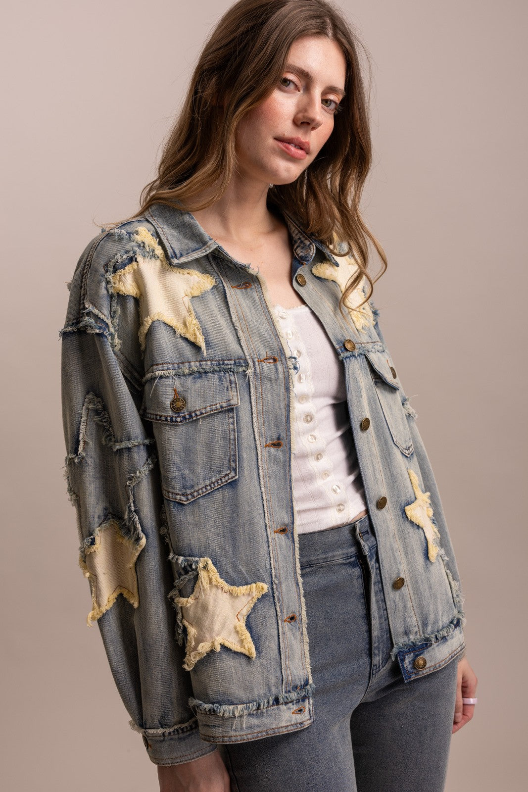 Angled view of BlueVelvet star patchwork denim jacket showing frayed seams, front buttons and relaxed sleeves