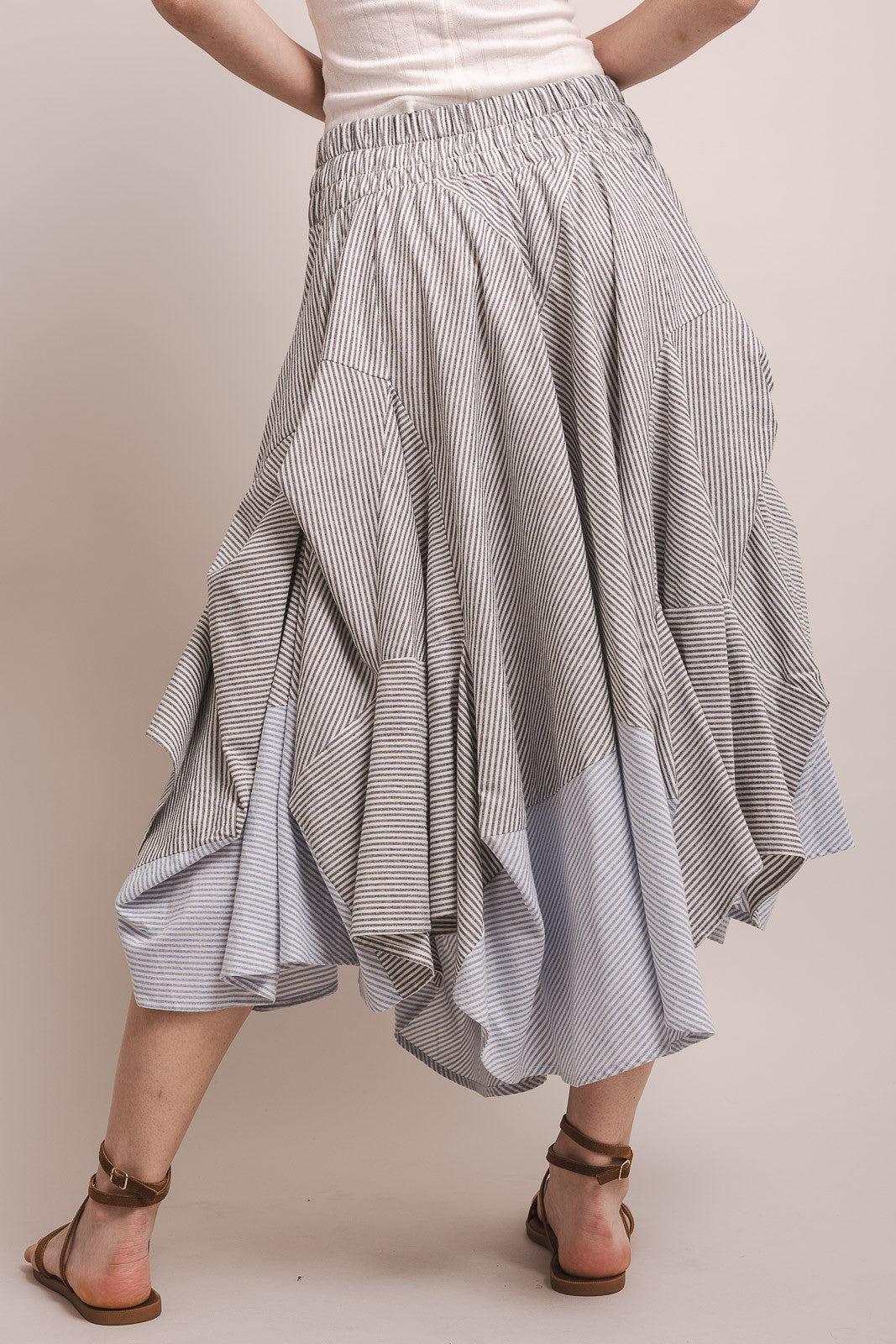 Person wearing a blue and white striped skirt on a plain background
