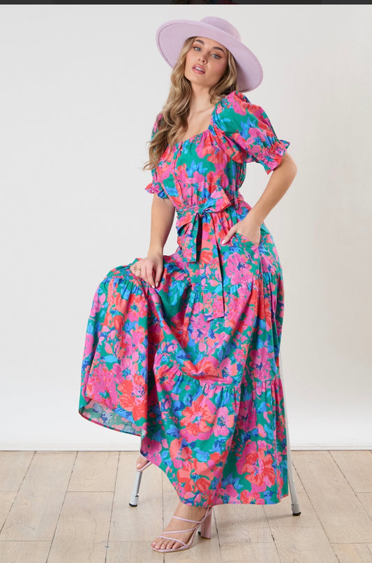 Bloom Into Beautiful Maxi Dress by Peach Love featuring a vibrant floral print, square neckline, puff sleeves, tie waist, tiered cotton skirt, and side pockets.