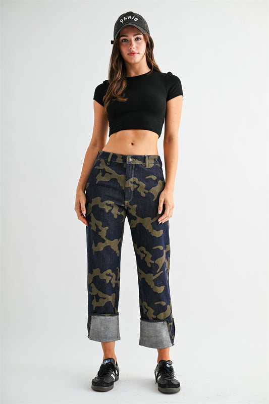 Model wearing stretchy high-rise camo cropped jeans by Mica Denim featuring rolled cuffs, dark wash denim, and olive camouflage print.