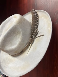 Silver feather-shaped brooch on a white stone surface with a dark brown background.
A Rare Bird
